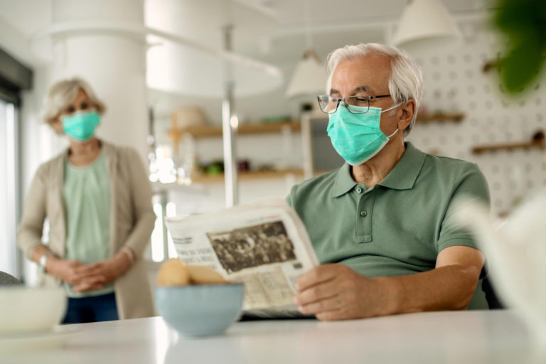 mature-man-with-protective-face-mask-reading-newspaper-home